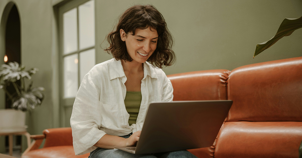 woman smiling and typing on a laptop