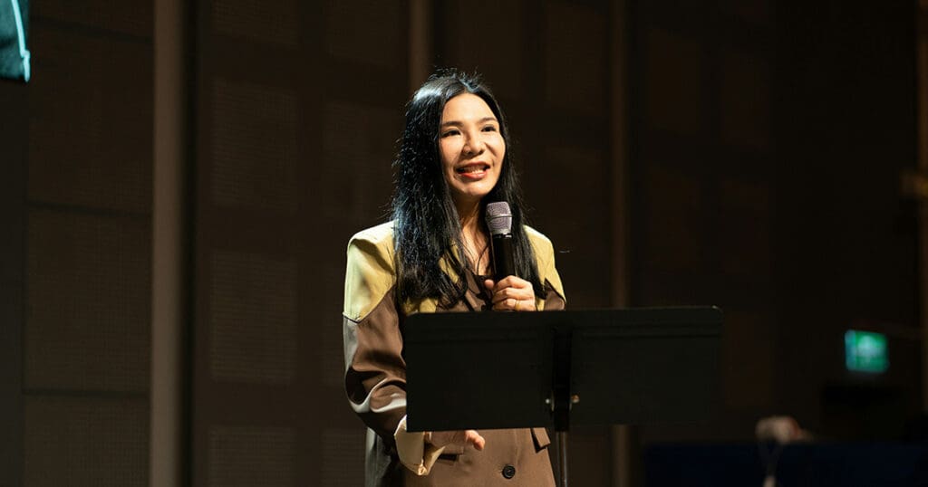 woman speaking on stage with a mic
