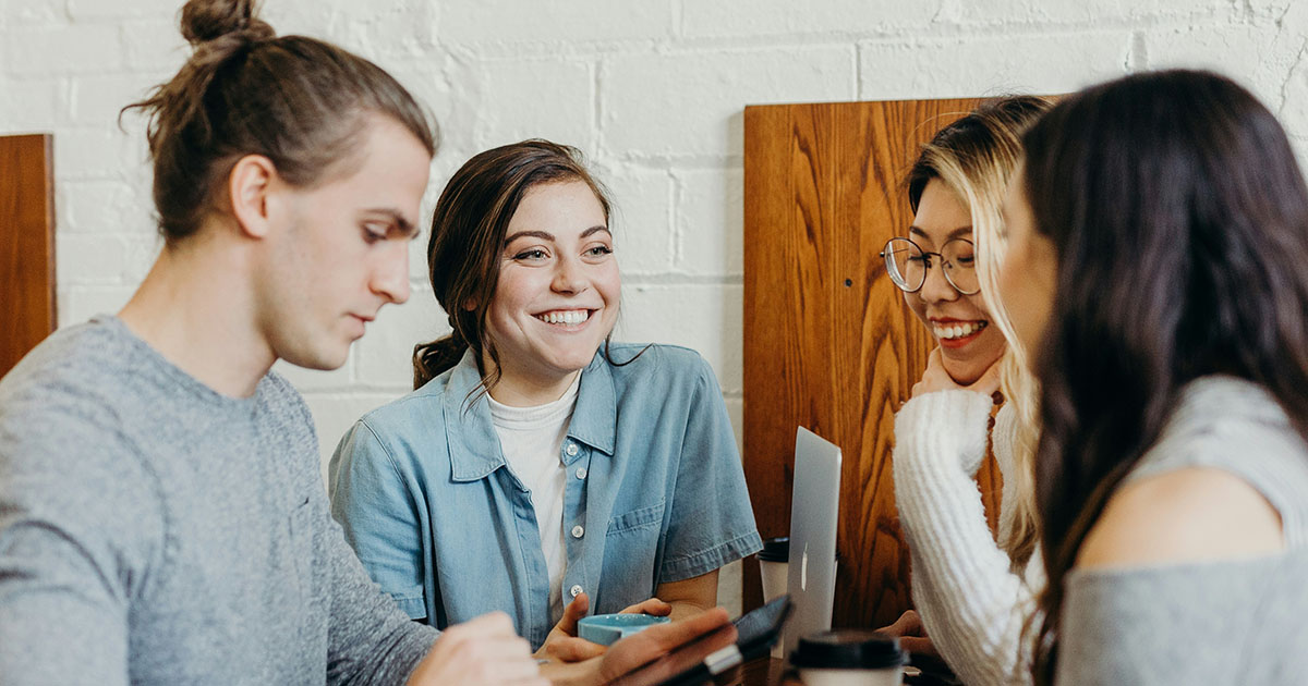 four young people laughing and working together on computers