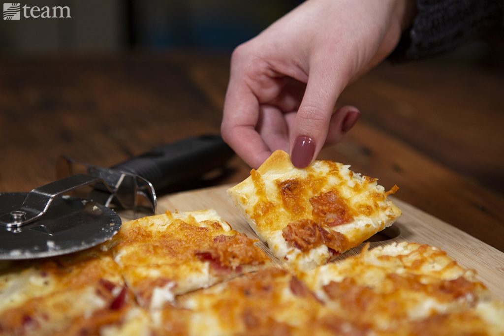 A woman grabs a slice of flammkuchen