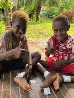 two boys giving a thumbs up after receiving medical care
