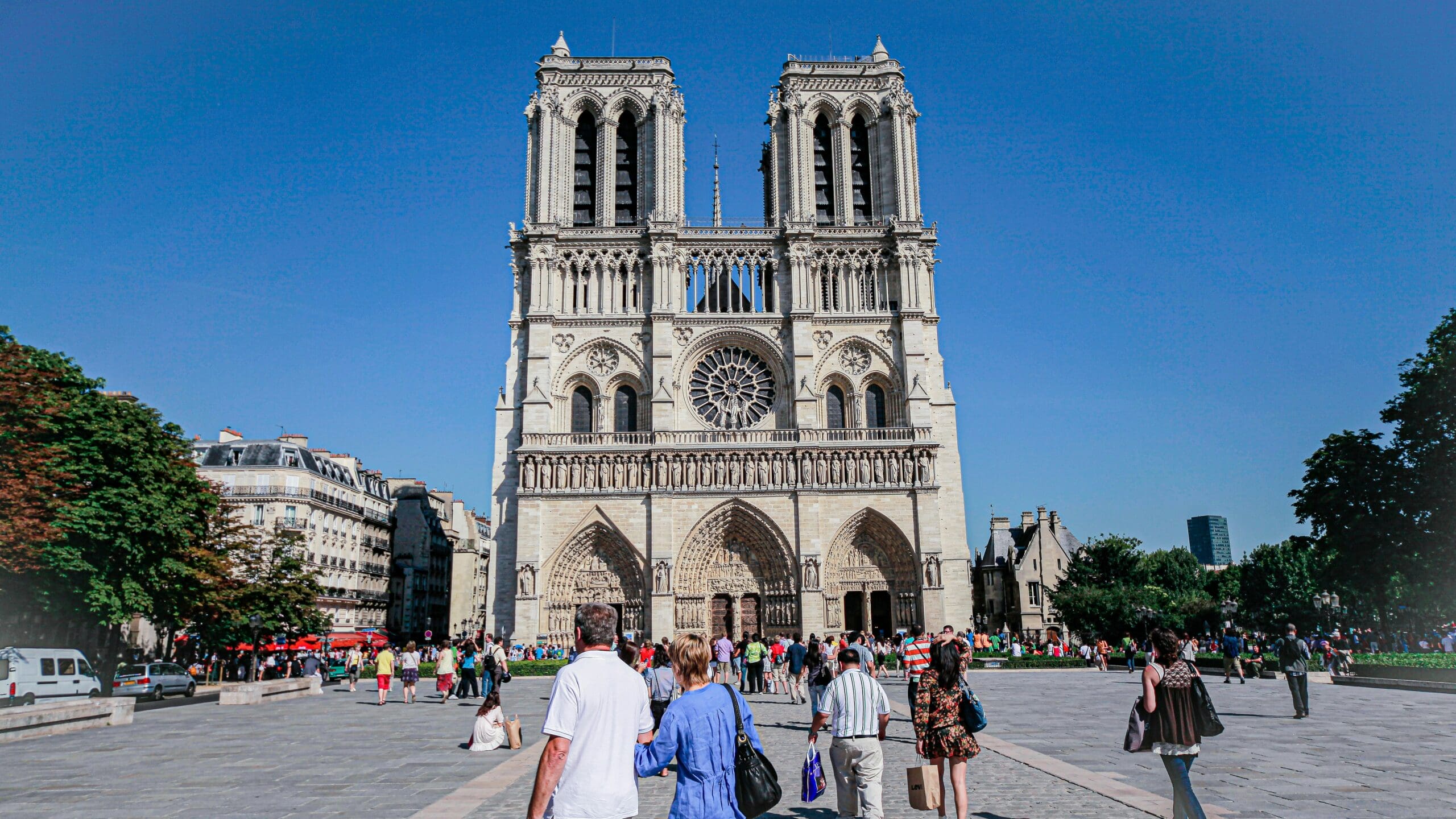 notre dame building with blue sky and tourists