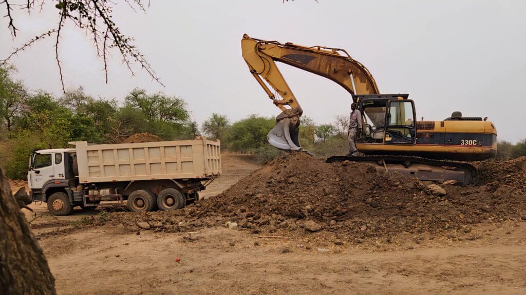 excavator and dump truck at the site of a community development project in chad