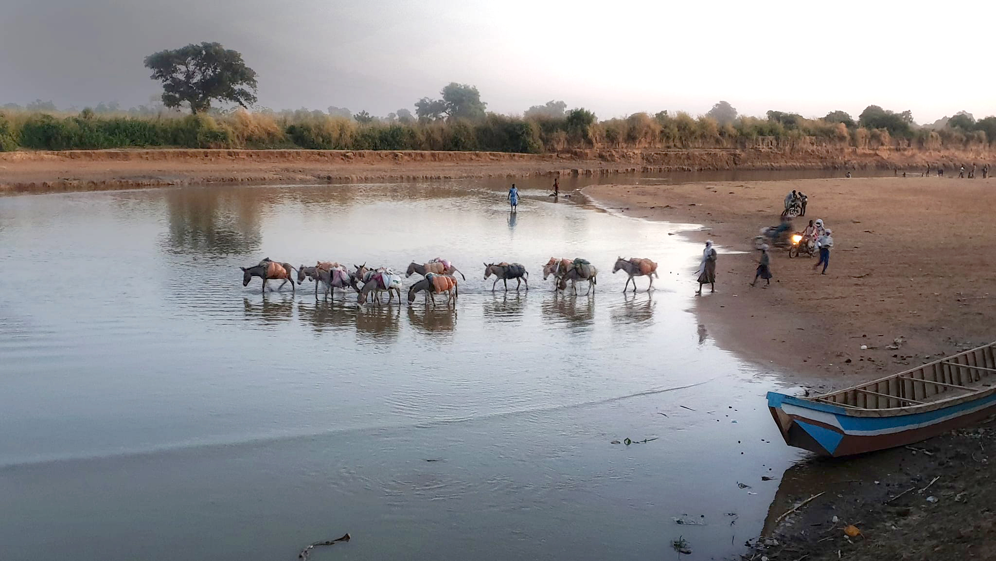 People and animals crossing a flowing river.