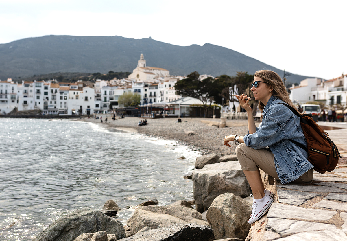 Woman sitting on the coast in Portugal talking on her cell phone.