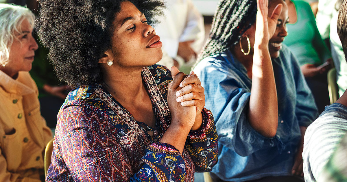 women with hands together praying to represent a missional church