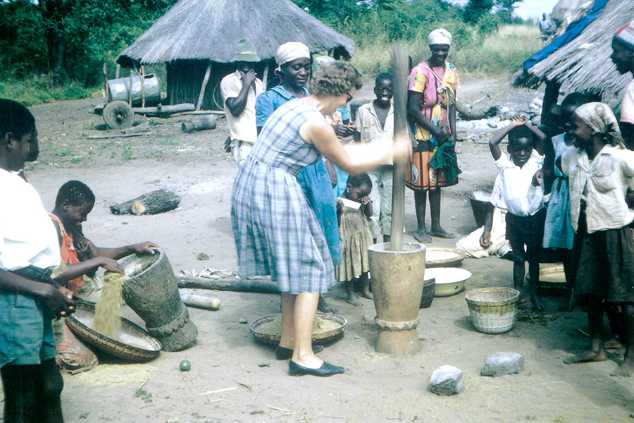 women on mission trip in avenue of service to god with group of people crushing maize