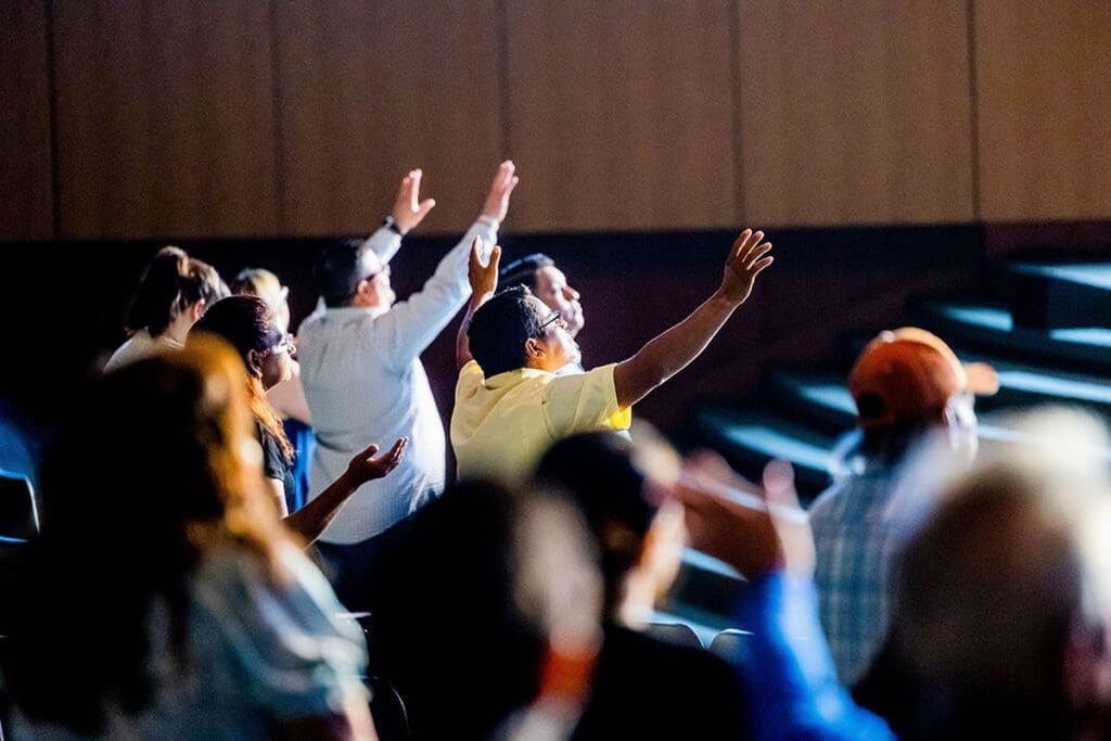 people raising their arms in worship at a missional church